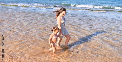 Beautiful mother and daughter playing at the beach