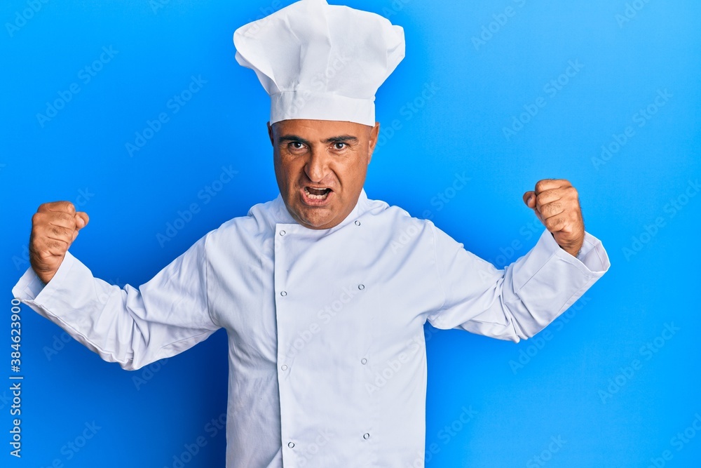 Mature middle east man wearing professional cook uniform and hat showing arms muscles smiling proud. fitness concept. Mature middle east man wearing professional cook uniform and hat showing arms muscles smiling proud. fitness concept.