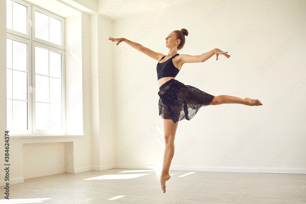 Slender young woman dancing in studio, practicing fouette jumps, getting ready for the show