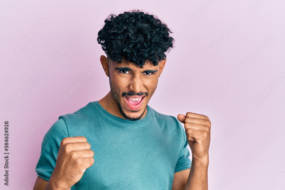 Young arab handsome man wearing casual clothes excited for success with arms raised and eyes closed celebrating victory smiling. winner concept. Young arab handsome man wearing casual clothes excited for success with arms raised and eyes closed celebrating victory smiling. winner concept.