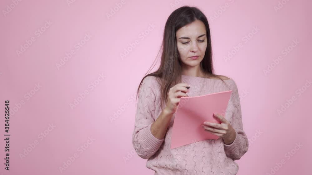 Pensive beautiful caucasian young woman writes a shopping list Pensive beautiful caucasian young woman writes a shopping list