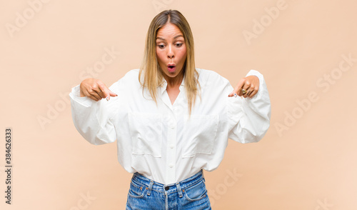 Konstfotografi young pretty woman feeling shocked, open-mouthed and amazed, looking and pointin
