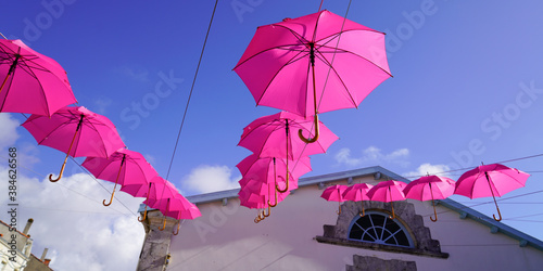 Fototapeta Naklejka Na Ścianę i Meble -  pink umbrellas hang between houses street decorated