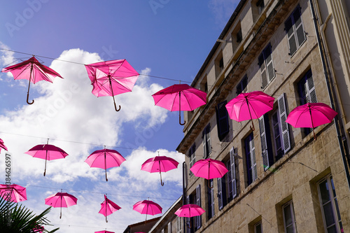 Multiple pink umbrellas hanging in october month over the street