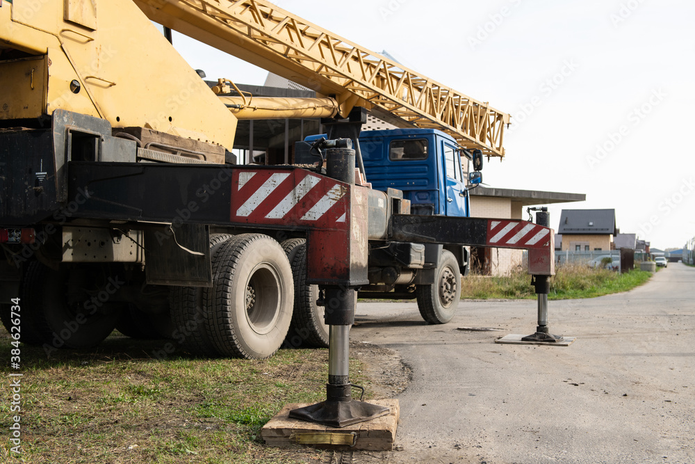 Obraz premium Mobile crane on construction site using hydraulic supports