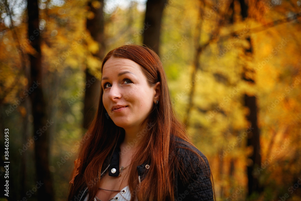 A red-haired girl in an autumn Park, against a background of yellow leaves. A red-haired girl in an autumn Park, against a background of yellow leaves.