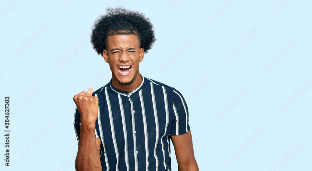 African american man with afro hair wearing casual clothes angry and mad raising fist frustrated and furious while shouting with anger. rage and aggressive concept. African american man with afro hair wearing casual clothes angry and mad raising fist frustrated and furious while shouting with anger. rage and aggressive concept.