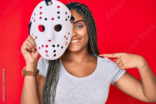 Photography Young african american woman with braids wearing hockey mask pointing finger to