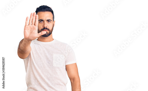 Young hispanic man wearing casual clothes doing stop sing with palm of the hand. warning expression with negative and serious gesture on the face.