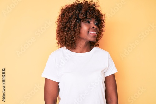 Young african american woman wearing casual white t shirt looking to side, relax profile pose with natural face and confident smile.