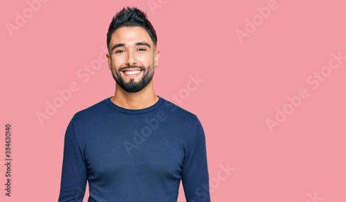 Young man with beard wearing casual blue winter sweater looking positive and happy standing and smiling with a confident smile showing teeth