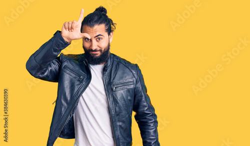 Young arab man wearing casual leather jacket making fun of people with fingers on forehead doing loser gesture mocking and insulting. © Krakenimages.com