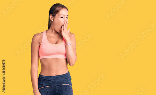 Young beautiful hispanic woman wearing sportswear bored yawning tired covering mouth with hand. restless and sleepiness.