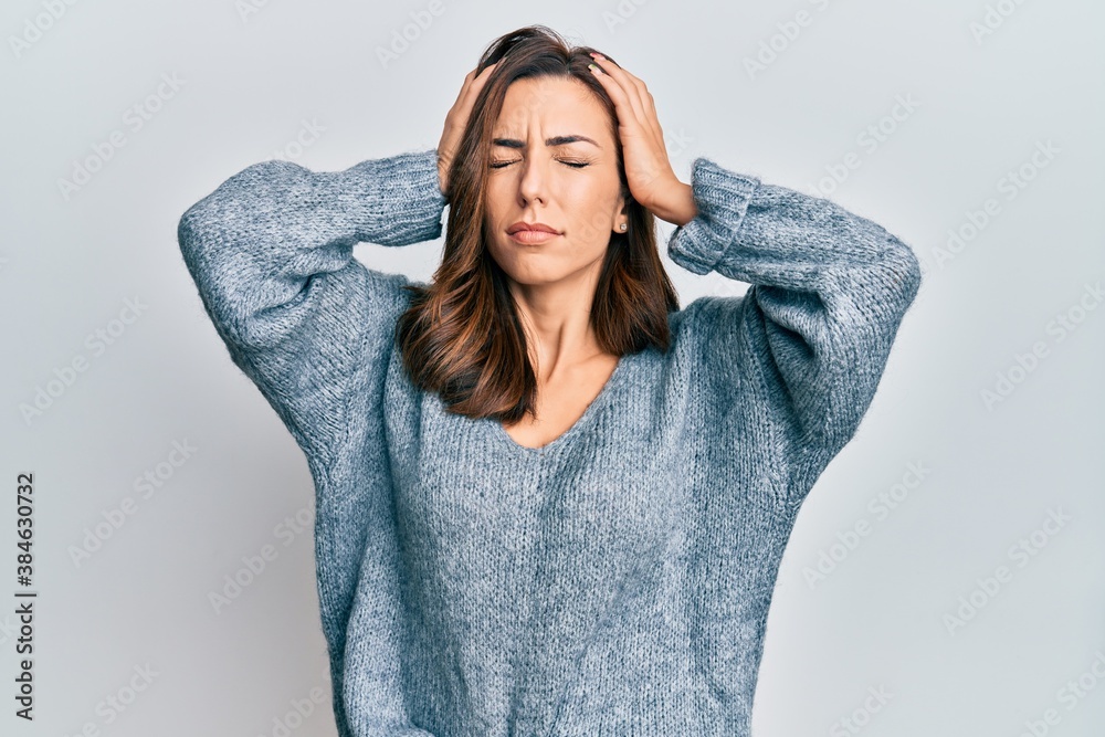 Young brunette woman wearing casual winter sweater suffering from headache desperate and stressed because pain and migraine. hands on head. Young brunette woman wearing casual winter sweater suffering from headache desperate and stressed because pain and migraine. hands on head.