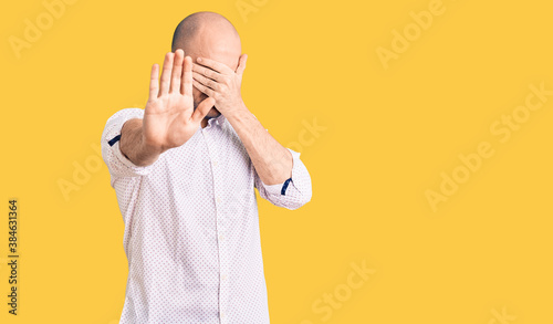 Young handsome man wearing elegant shirt covering eyes with hands and doing stop gesture with sad and fear expression. embarrassed and negative concept.