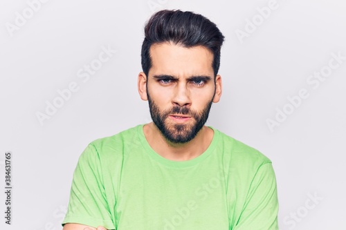 Young handsome man with beard wearing casual t-shirt skeptic and nervous, disapproving expression on face with crossed arms. negative person.