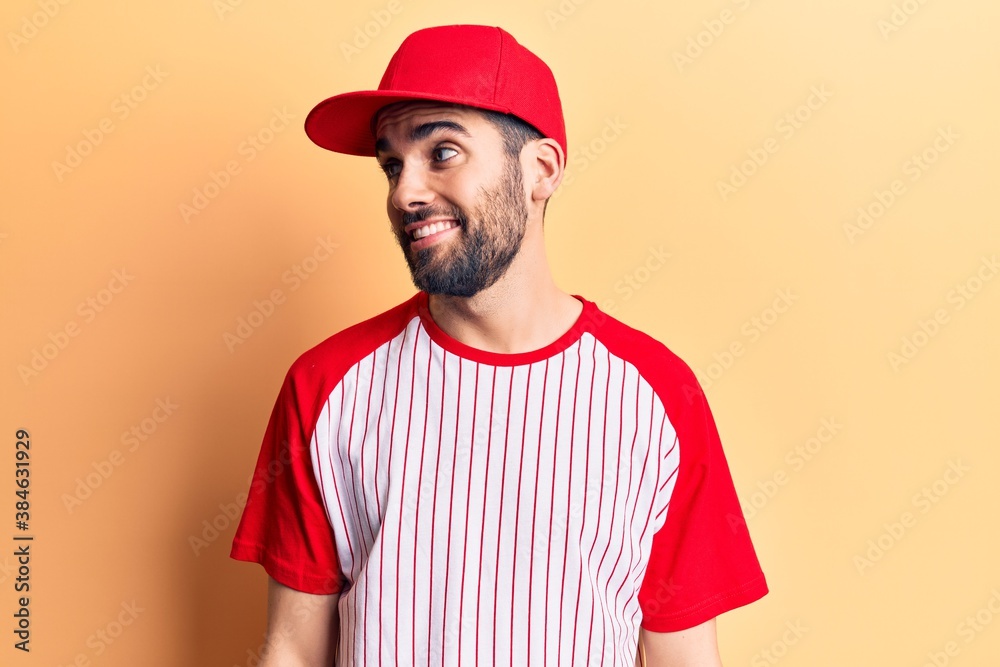 Young handsome man with beard wearing baseball cap and t-shirt looking to side, relax profile pose with natural face and confident smile.