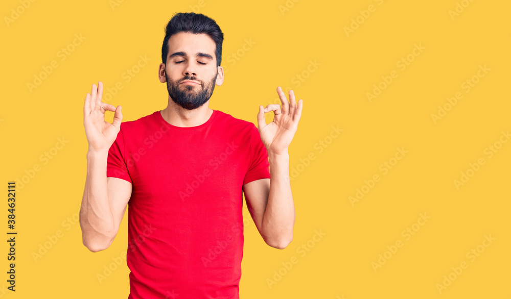 Young handsome man with beard wearing casual t-shirt relax and smiling with eyes closed doing meditation gesture with fingers. yoga concept. Young handsome man with beard wearing casual t-shirt relax and smiling with eyes closed doing meditation gesture with fingers. yoga concept.
