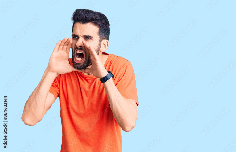 Young handsome man with beard wearing casual t-shirt shouting angry out loud with hands over mouth Young handsome man with beard wearing casual t-shirt shouting angry out loud with hands over mouth