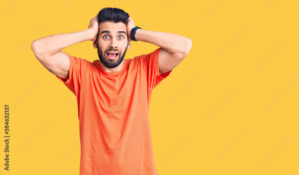 Young handsome man with beard wearing casual t-shirt crazy and scared with hands on head, afraid and surprised of shock with open mouth Young handsome man with beard wearing casual t-shirt crazy and scared with hands on head, afraid and surprised of shock with open mouth