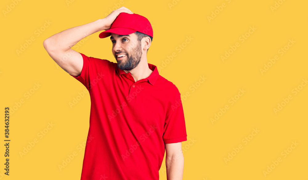Young handsome man with beard wearing delivery uniform smiling confident touching hair with hand up gesture, posing attractive and fashionable Young handsome man with beard wearing delivery uniform smiling confident touching hair with hand up gesture, posing attractive and fashionable