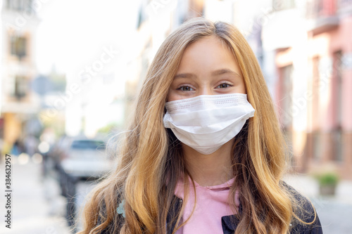 Close up portrait little girl 8 years old wearing protective mask for good air outdoor. Air pollution and Coronavirus concept.
