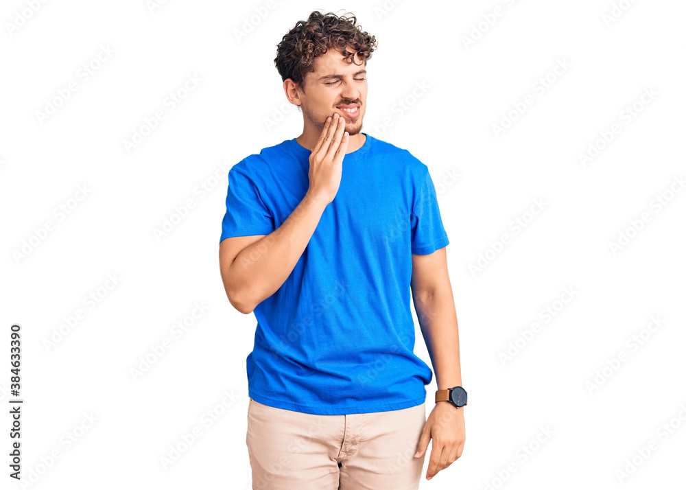 Young handsome man with curly hair wearing casual clothes touching mouth with hand with painful expression because of toothache or dental illness on teeth. dentist