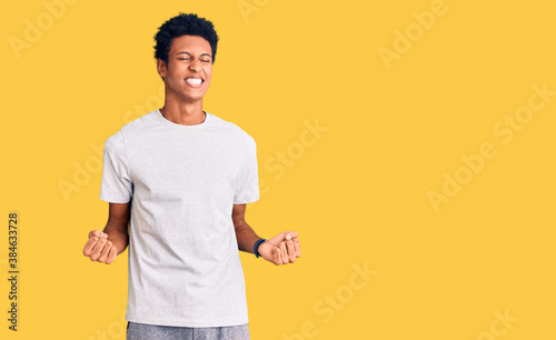 Young african american man wearing casual clothes very happy and excited doing winner gesture with arms raised, smiling and screaming for success. celebration concept.