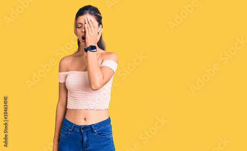 Young beautiful woman wearing casual clothes yawning tired covering half face, eye and mouth with hand. face hurts in pain.