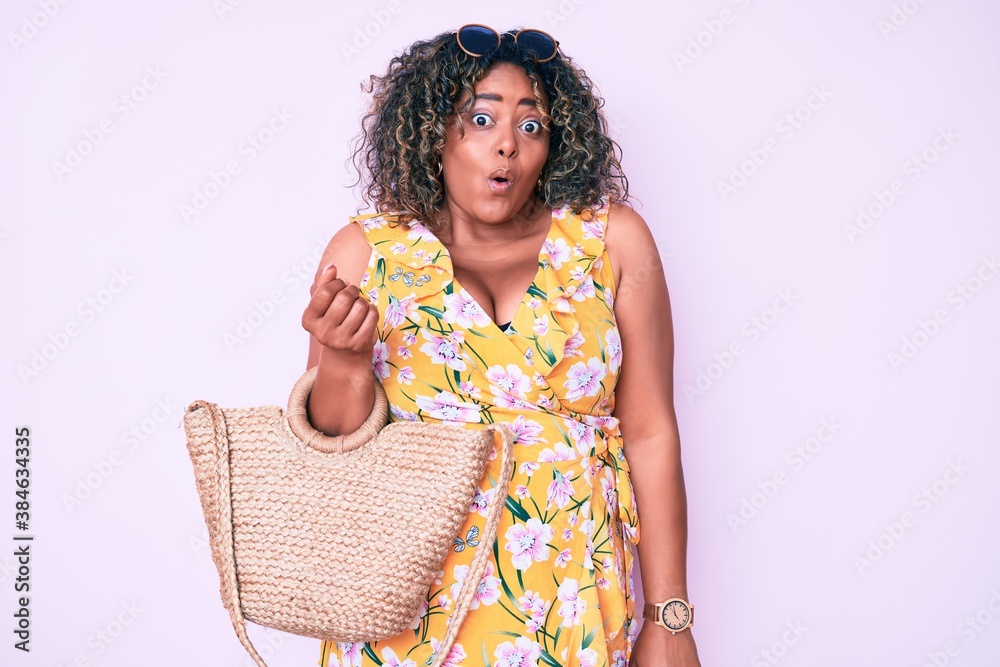 Young african american plus size woman wearing casual clothes holding summer wicker handbag scared and amazed with open mouth for surprise, disbelief face Young african american plus size woman wearing casual clothes holding summer wicker handbag scared and amazed with open mouth for surprise, disbelief face