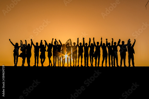 Silhouettes of children against the sunset with their hands up. Goodbye school. Prom. Banner. A place for text. Photo in the background of the sun. Friendship.