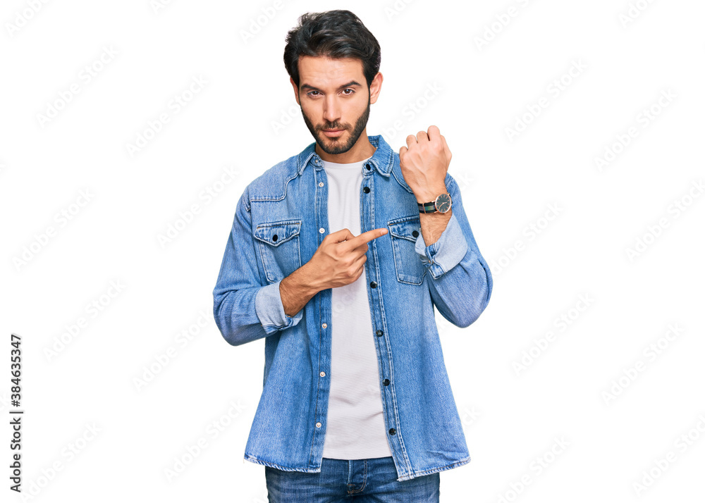 Young hispanic man wearing casual clothes in hurry pointing to watch time, impatience, looking at the camera with relaxed expression Young hispanic man wearing casual clothes in hurry pointing to watch time, impatience, looking at the camera with relaxed expression