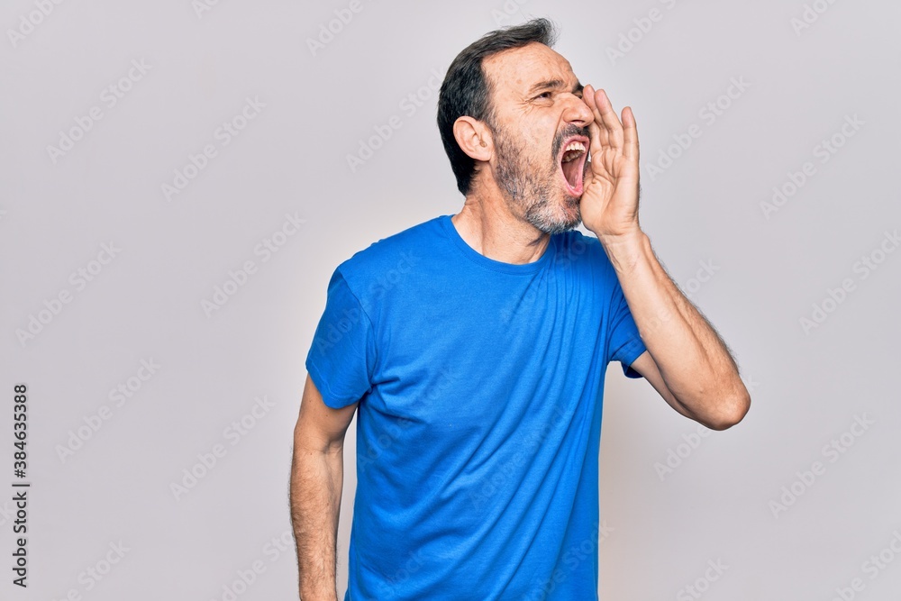 Middle age handsome man wearing casual t-shirt standing over isolated white background shouting and screaming loud to side with hand on mouth. Communication concept. Middle age handsome man wearing casual t-shirt standing over isolated white background shouting and screaming loud to side with hand on mouth. Communication concept.
