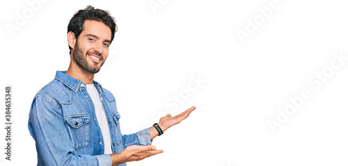 Fotografie Young hispanic man wearing casual clothes inviting to enter smiling natural with