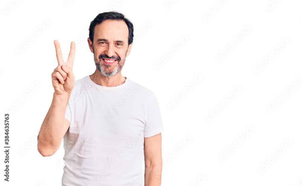 Fototapeta premium Middle age handsome man wearing casual t-shirt showing and pointing up with fingers number two while smiling confident and happy.