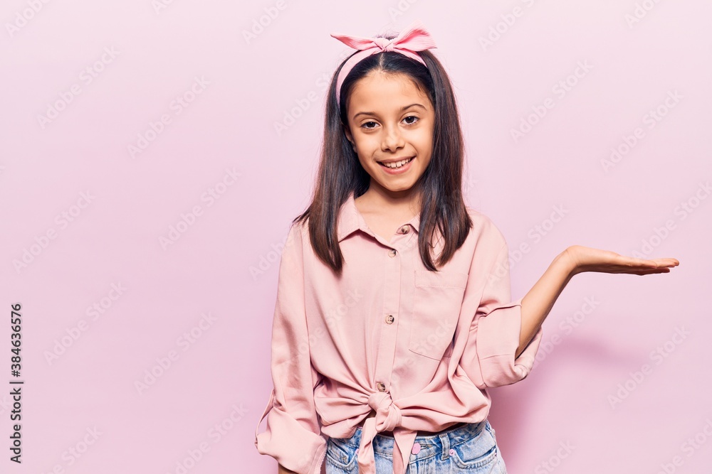 Beautiful child girl wearing casual clothes smiling cheerful presenting and pointing with palm of hand looking at the camera. Beautiful child girl wearing casual clothes smiling cheerful presenting and pointing with palm of hand looking at the camera.