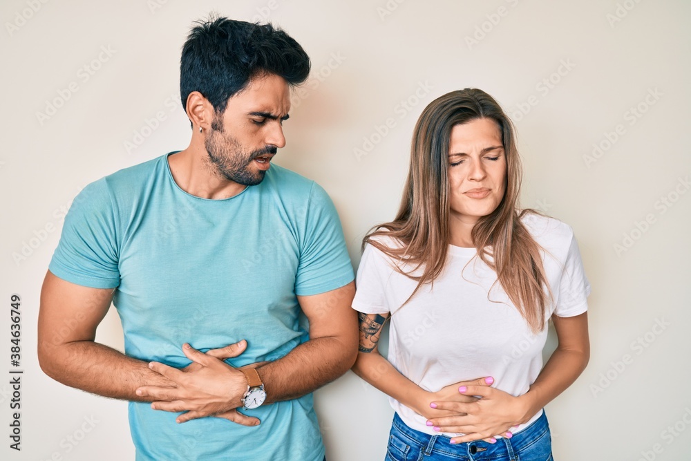 Beautiful young couple of boyfriend and girlfriend together with hand on stomach because indigestion, painful illness feeling unwell. ache concept. Beautiful young couple of boyfriend and girlfriend together with hand on stomach because indigestion, painful illness feeling unwell. ache concept.