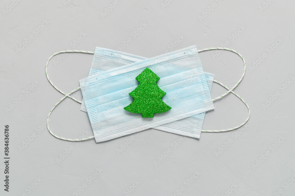 New normal. Medical protective masks and Christmas decorations on a light gray background. Top view, minimalism. Minimal Christmas concept.