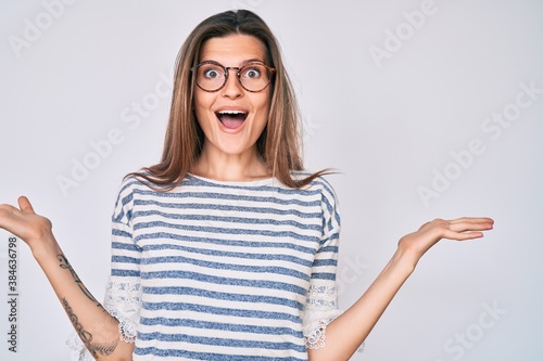 Beautiful caucasian woman wearing casual clothes and glasses celebrating victory with happy smile and winner expression with raised hands
