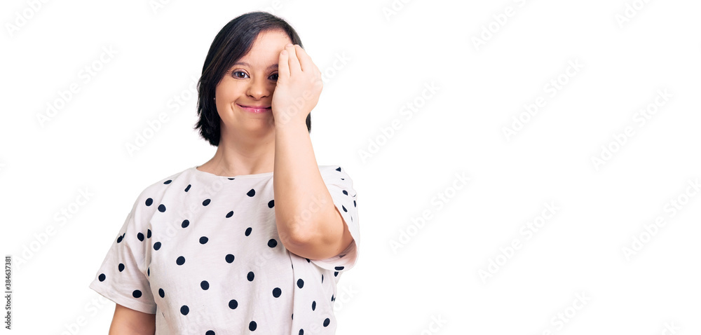 Brunette woman with down syndrome wearing casual clothes covering one eye with hand, confident smile on face and surprise emotion. Brunette woman with down syndrome wearing casual clothes covering one eye with hand, confident smile on face and surprise emotion.