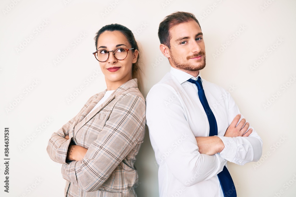 Beautiful couple wearing business clothes looking to the side with arms crossed convinced and confident Beautiful couple wearing business clothes looking to the side with arms crossed convinced and confident