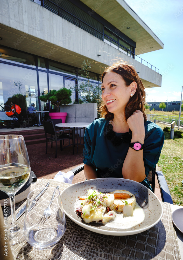 Beautiful young woman on the open terrace of the restaurant with a glass of wine