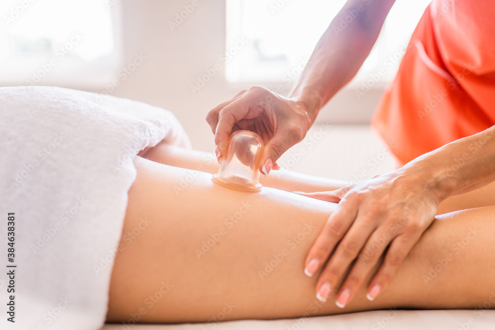 Masseur make massage with jars of cellulite on the buttock and thighs of patient. Treatment of excess weight, anti-cellulite, skin care Masseur make massage with jars of cellulite on the buttock and thighs of patient. Treatment of excess weight, anti-cellulite, skin care