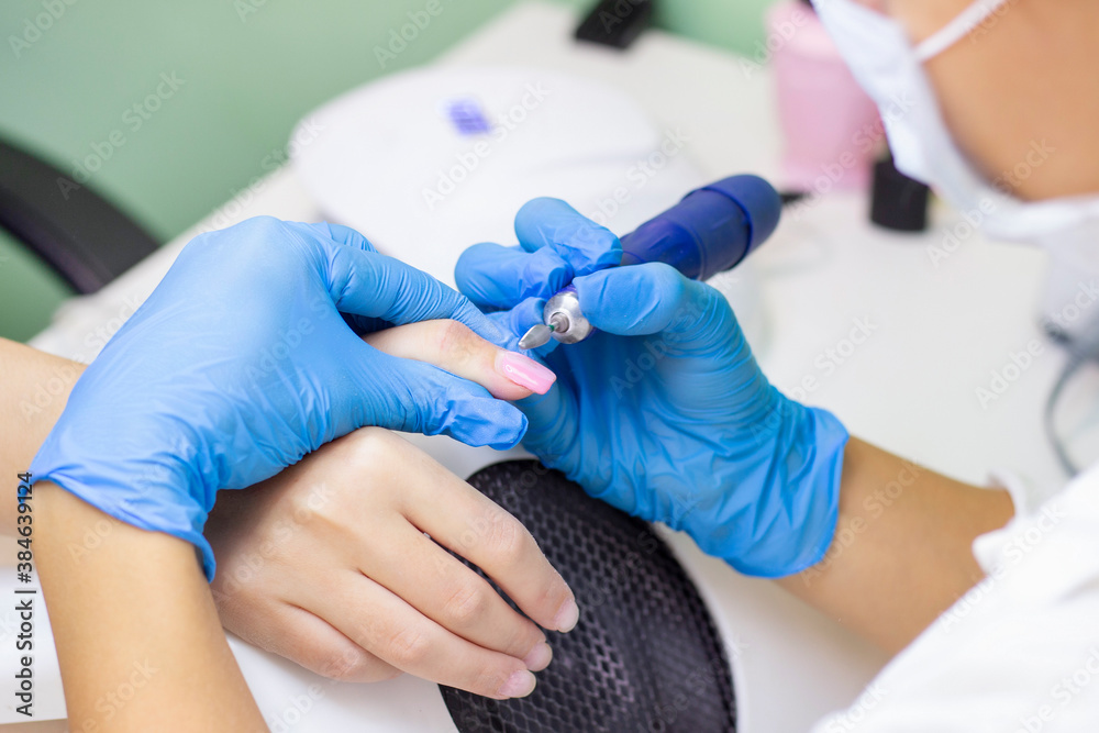 Manicurist polishes the surface of the nail and skin before applying the gel for nails