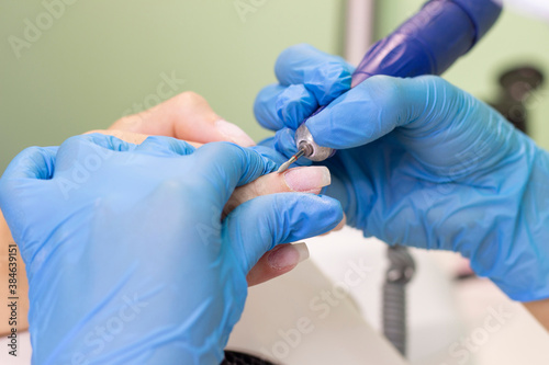 Manicurist polishes the surface of the nail and skin before applying the gel for nails