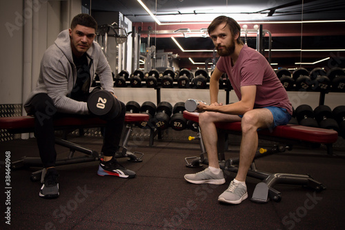 Fotografie beginner sport man and personal trainer sit on bench with dumbbells and sports exercise