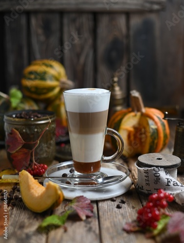 Pumpkin spice latte with whipped cream and cinnamon in glass on rustic wooden background. Selective focus.