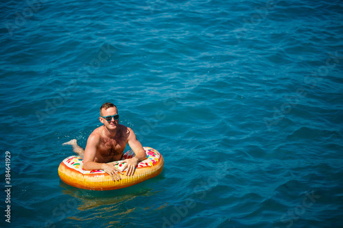 Young man on an inflatable ring in the sea resting and swimming on a sunny day © Дмитрий Ткачук