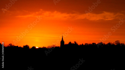 Church steeple and tree silhouette at sunset