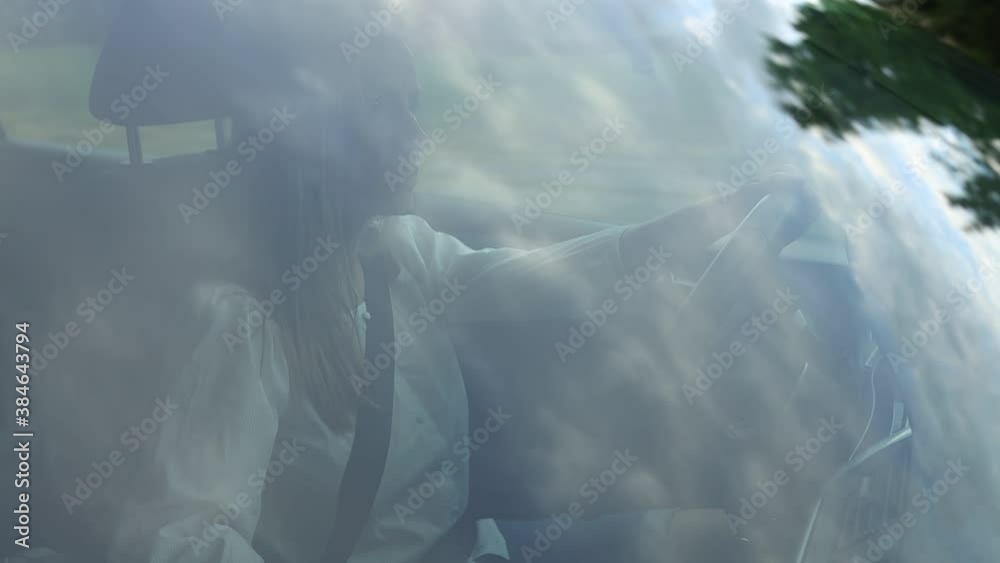 Pretty, middle aged woman driving her car in a city, on a highway. Scenery passing by, reflecting in the windshield. Pretty, middle aged woman driving her car in a city, on a highway. Scenery passing by, reflecting in the windshield.